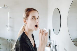 a woman washing her face with the leftover toothbrush water